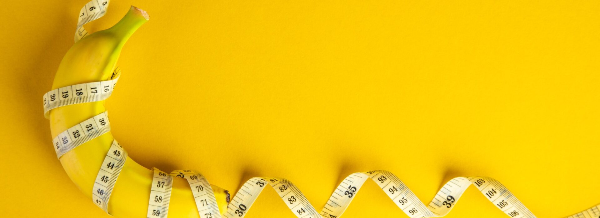 Banana and tape measure on yellow background. Diet concept.