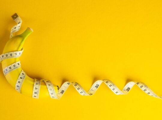 Banana and tape measure on yellow background. Diet concept.