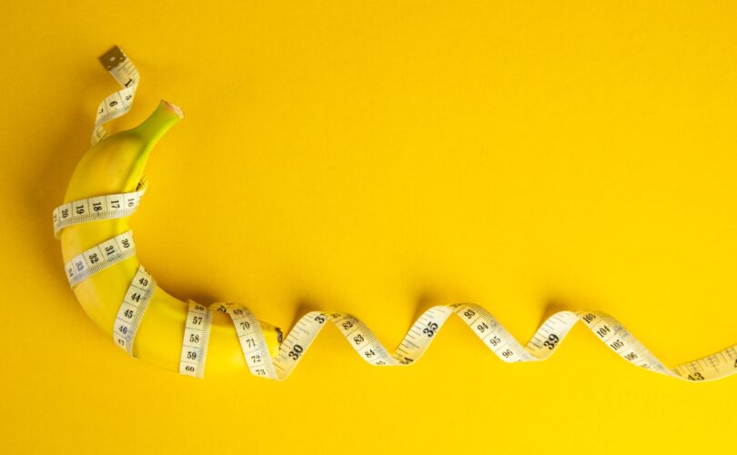 Banana and tape measure on yellow background. Diet concept.