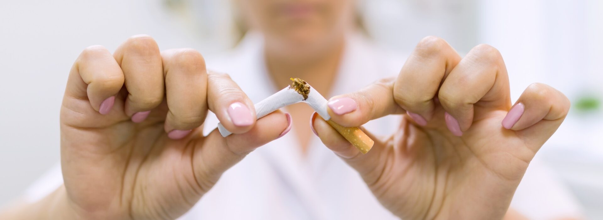 Doctor dentist breaks a cigarette, broken cigarette close up, background dental office. Stop Smoking
